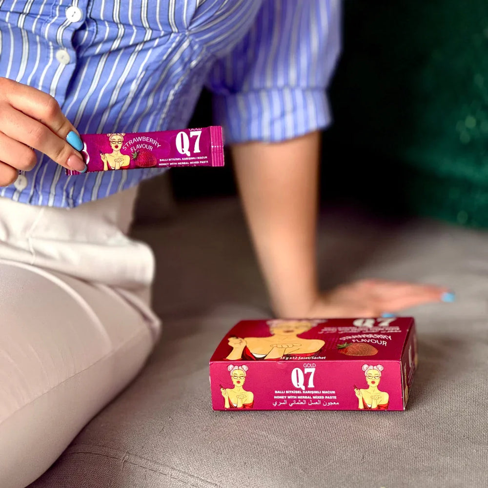 Жена държи саше от Епимедиум Маджун Q7 Gold за жени, опаковка с 12 сашета, ягодов аромат.